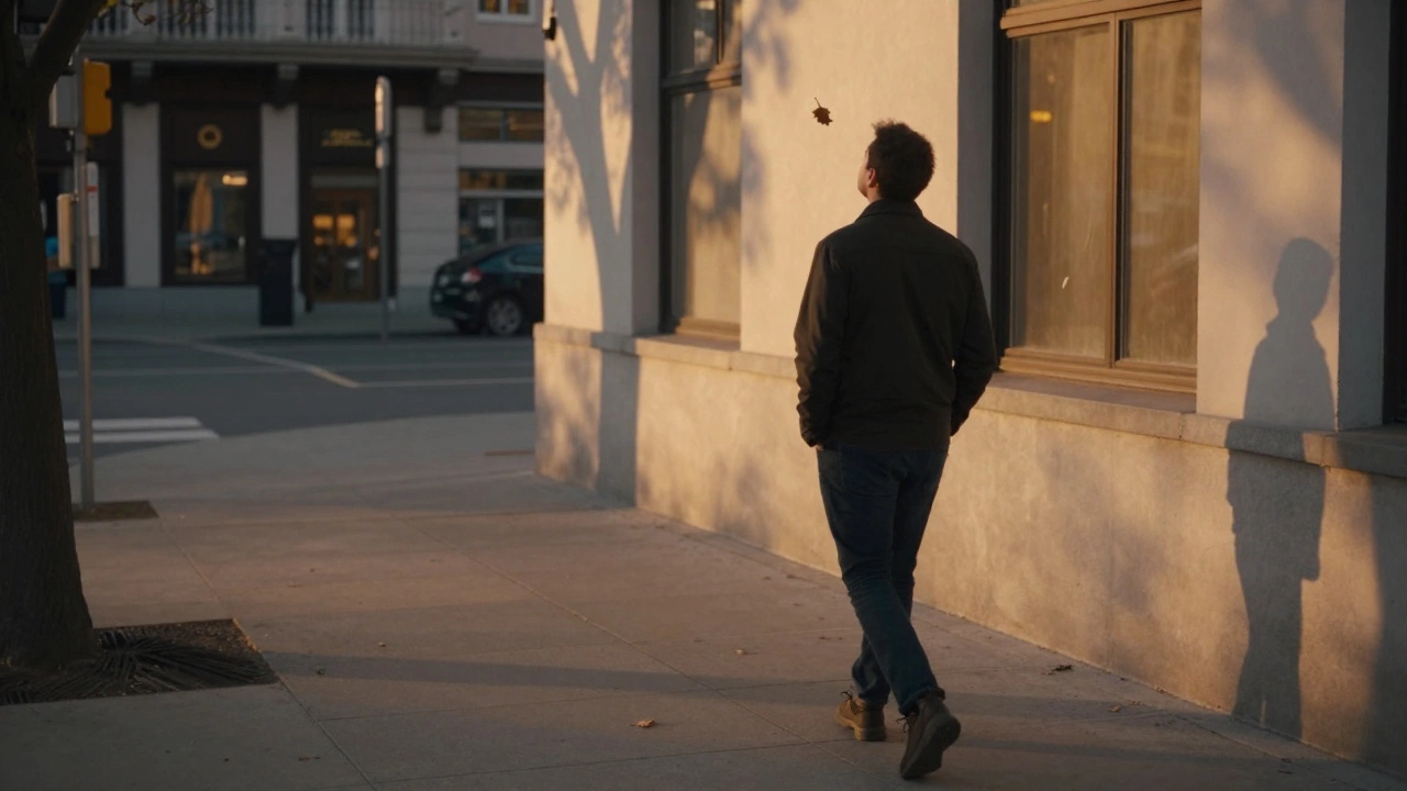 Мужчина гуляет без телефона в сумерках, смотрит на падающий лист и светящееся окно.